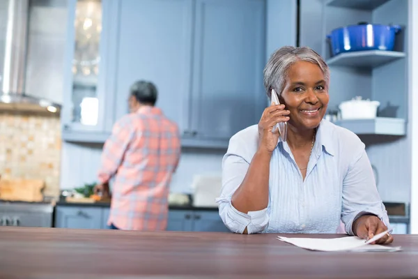 Kobieta mówi telefon stojąc w kuchni — Zdjęcie stockowe