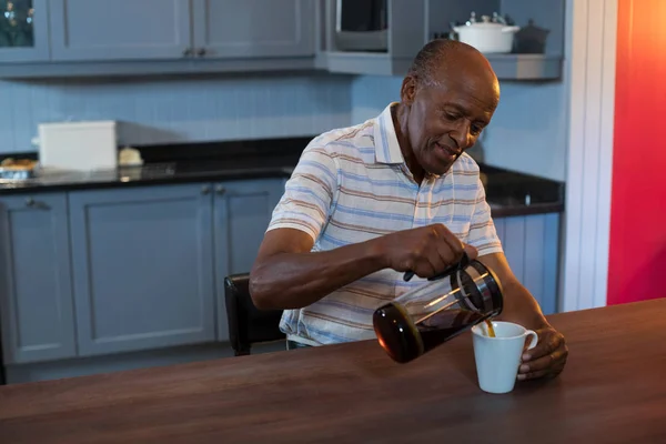 Старший мужчина наливает кофе в чашку — стоковое фото