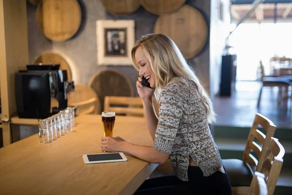 Woman talking on mobile phone at bar counter — Stock Photo, Image