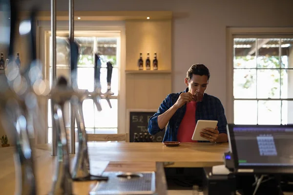 Hombre usando tableta digital mientras toma café — Foto de Stock
