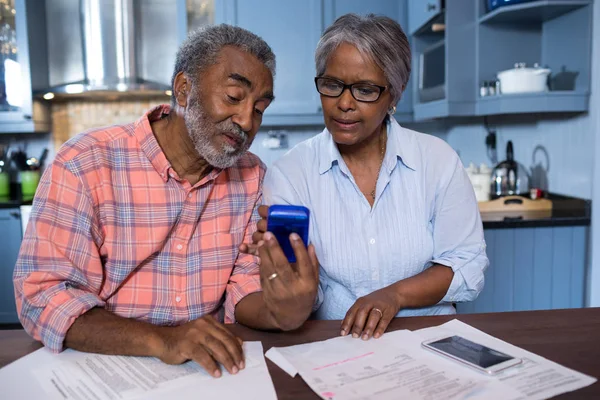 Pareja usando calculadora en cocina — Foto de Stock