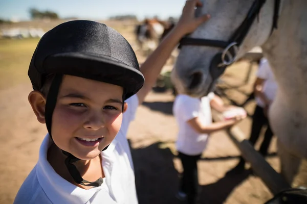 Sorrindo cavaleiro menino tocando o cavalo branco — Fotografia de Stock