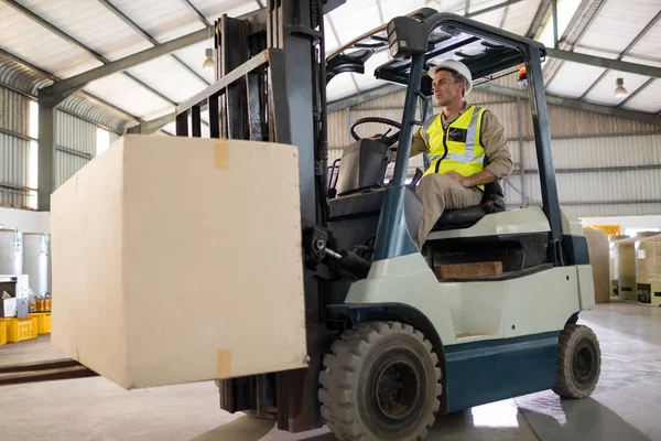 Worker carrying package with forklift — Stock Photo, Image