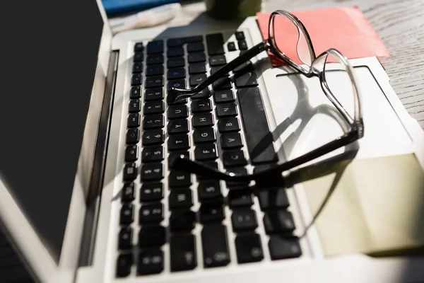 Brillen op laptopcomputer aan tafel — Stockfoto