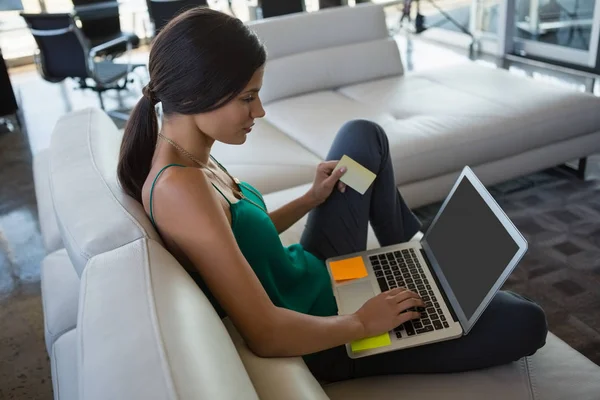 Donna che utilizza il computer portatile mentre si rilassa sul divano — Foto Stock