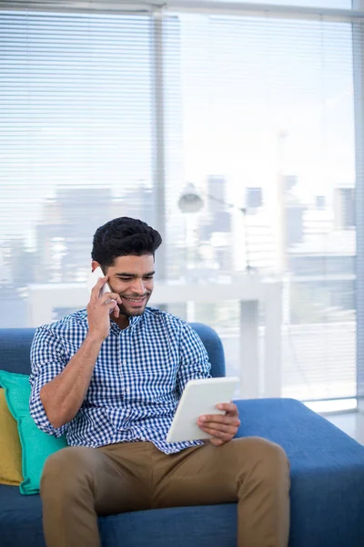 Male executive using tablet talking on phone — Stock Photo, Image