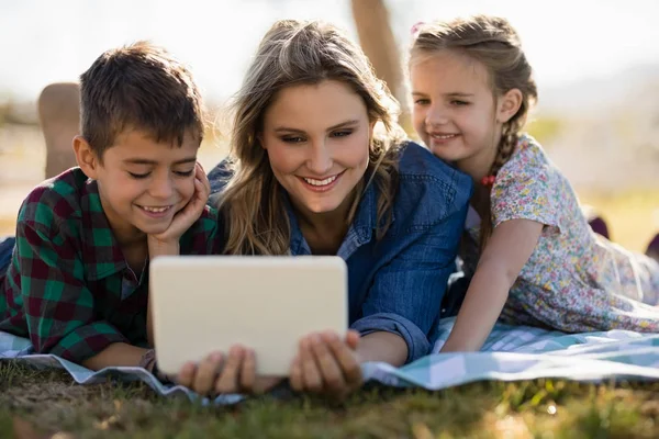 母亲和孩子们在公园里使用数字平板电脑 — 图库照片
