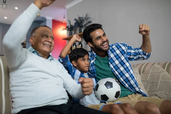 Сім'я з піднятими руками дивиться футбольний матч — стокове фото
