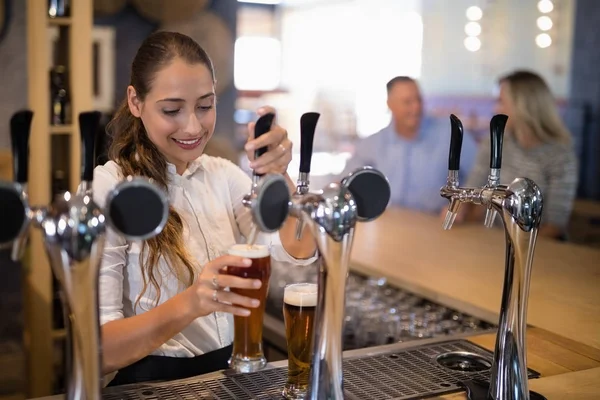 Female bartender filling beer from bar pump — Stock Photo, Image
