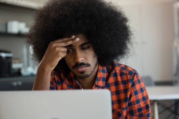 Trött man tittar in i laptop på kontoret — Stockfoto