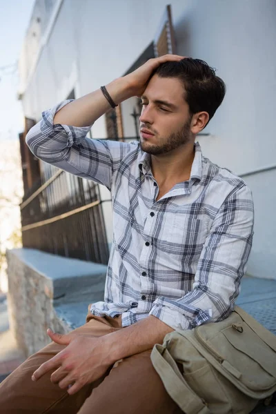 Mann mit geschlossenen Augen sitzt auf Stützmauer — Stockfoto