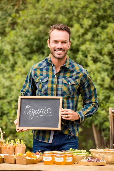 Man with blackboard selling vegetables — Stock Photo, Image