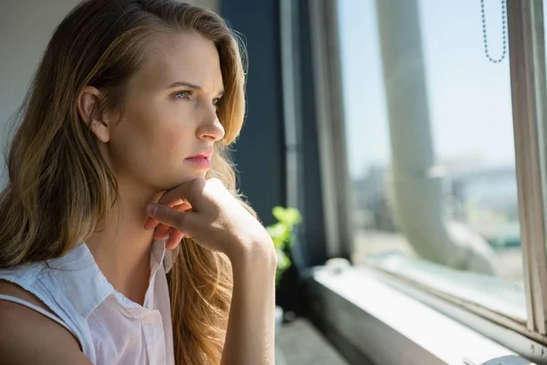 Tankeväckande affärskvinna tittar genom fönstret — Stockfoto