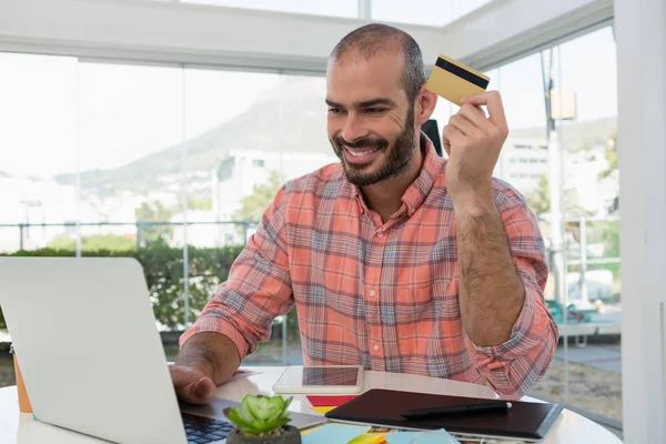 Designer gráfico segurando cartão de crédito — Fotografia de Stock