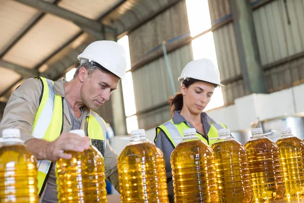 Trabalhadores verificando registros de garrafas de óleo — Fotografia de Stock