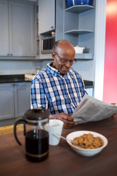 Adam kahvaltı yaparken gazete okuyor. — Stok fotoğraf