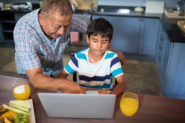 Grootvader van meewerkende kleinzoon met behulp van laptop — Stockfoto