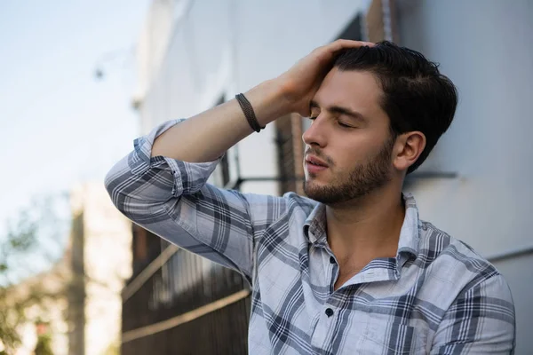 Tensed man sitting by wall