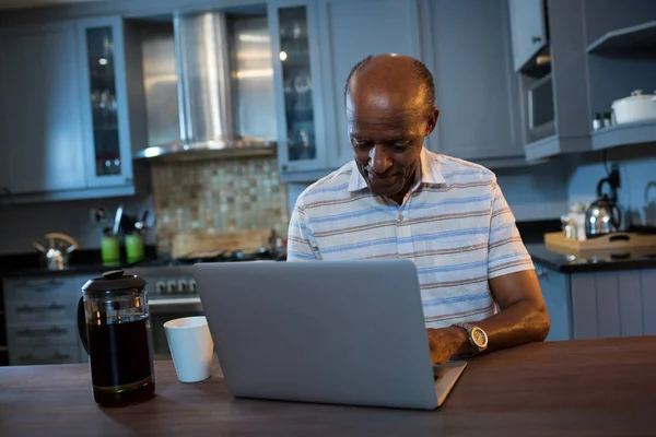 Człowiek za pomocą laptopa przy stole w kuchni — Zdjęcie stockowe
