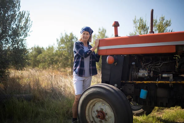 Mujer de pie cerca del tractor en la granja de olivos —  Fotos de Stock