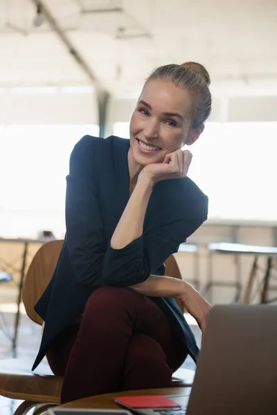 Geschäftsfrau mit Hand am Kinn auf Stuhl sitzend — Stockfoto