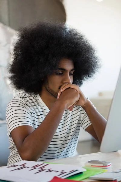 Hombre con el pelo rizado sentado en el escritorio — Foto de Stock