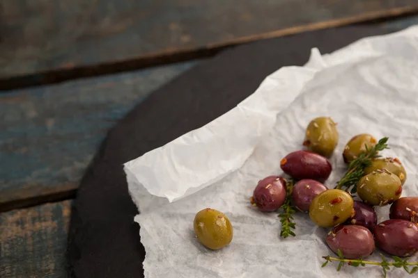 Green and brown olives on wax paper — Stock Photo, Image