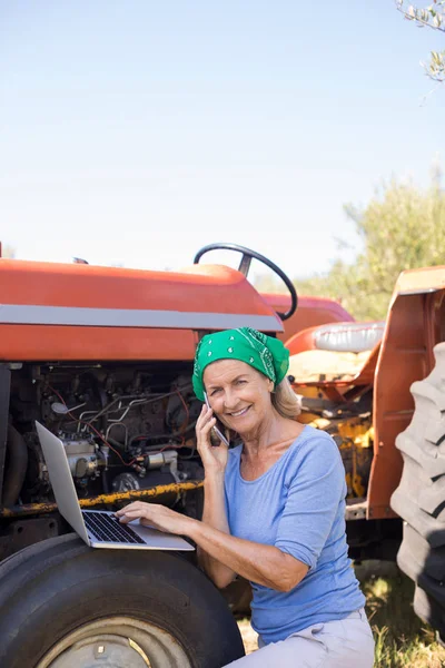 Kvinnan använder laptop medan du talar i telefon — Stockfoto