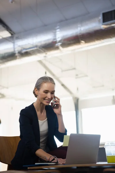 Donna che parla al telefono durante l'utilizzo del computer portatile — Foto Stock