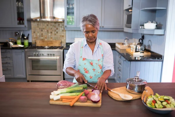 Mujer cortando verduras mientras prepara alimentos —  Fotos de Stock