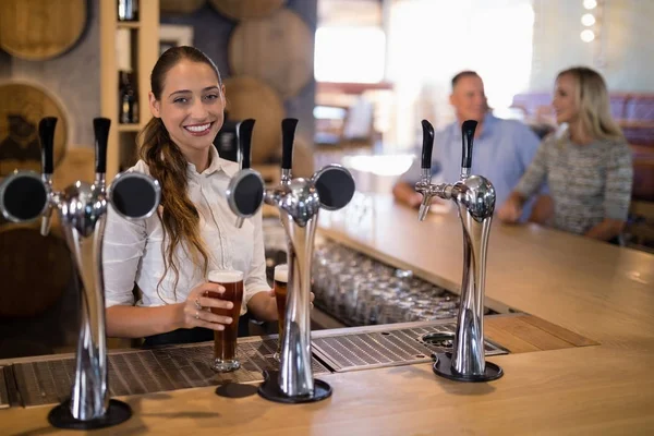 Female bartender holding glass of beer — Stock Photo, Image