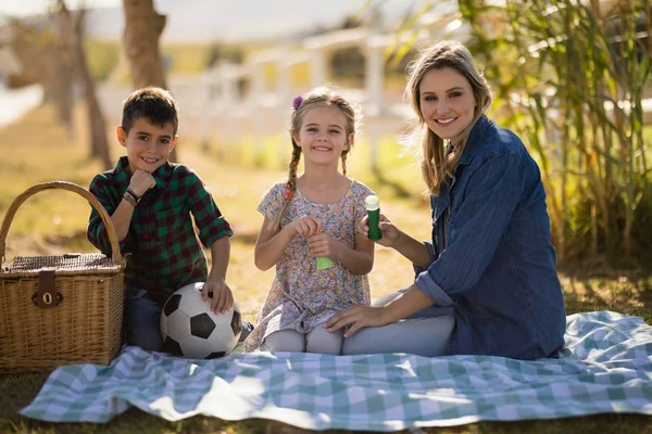 Mother and kids sitting together in park — Stock Photo, Image