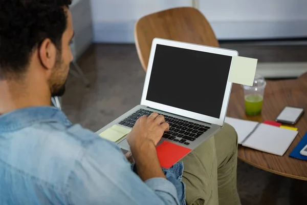 Человек работает во время использования ноутбука в офисе — стоковое фото