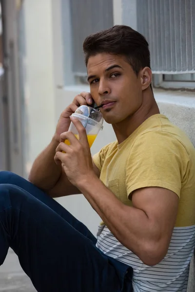 Homem beber suco enquanto fala no telefone inteligente — Fotografia de Stock