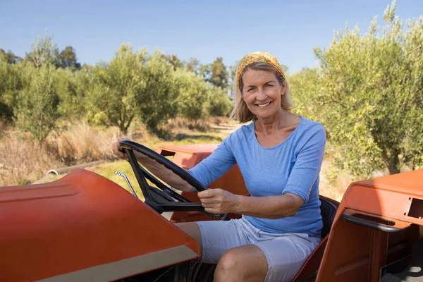 Femme heureuse assise dans le tracteur — Photo