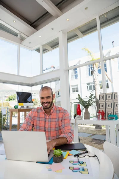 Designer using laptop while sitting at desk — Stock Photo, Image