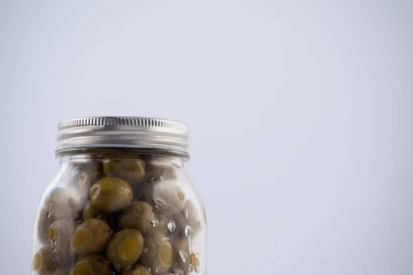 Зеленая оливка в стеклянной банке с серебряной крышкой — стоковое фото
