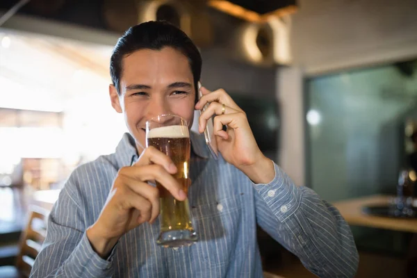 Homme prenant une bière tout en parlant au téléphone — Photo