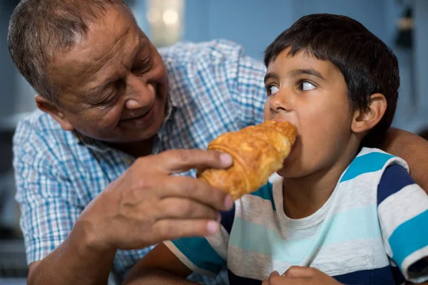 Nagyapa etetésére croissant unokája — Stock Fotó