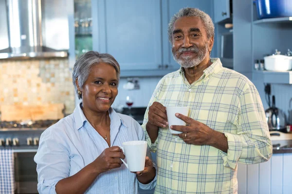 Smiling senior couple with coffee cups — Stock Photo, Image