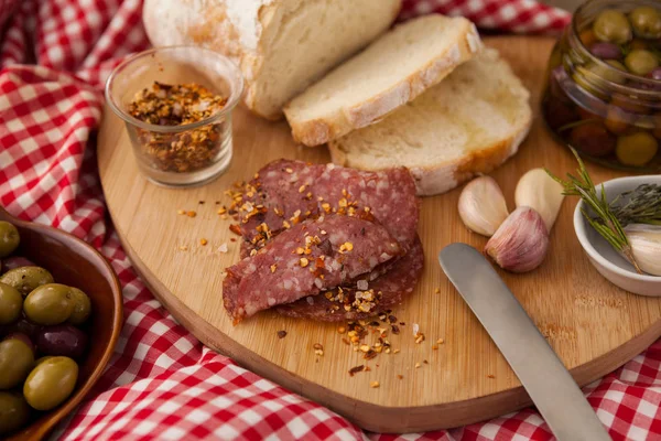 Chili flakes on meat by bread with olives — Stock Photo, Image