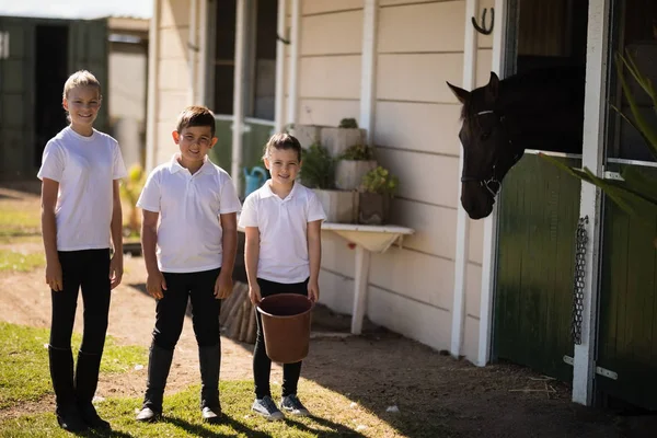 Crianças de pé com balde para alimentar o cavalo — Fotografia de Stock