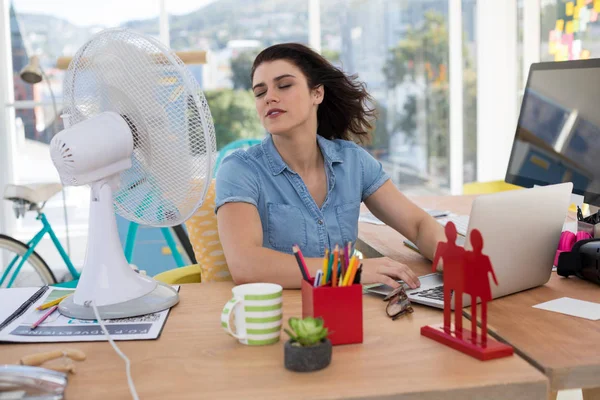 Executivo desfrutando brisa de ventilador de mesa — Fotografia de Stock