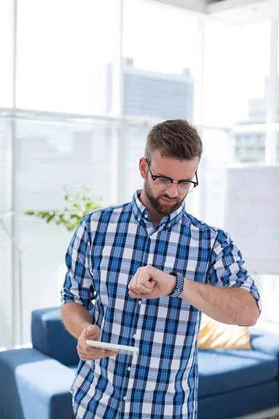 Male executive checking time on smartwatch — Stock Photo, Image