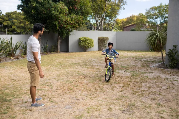 Pai olhando para filho andar de bicicleta — Fotografia de Stock