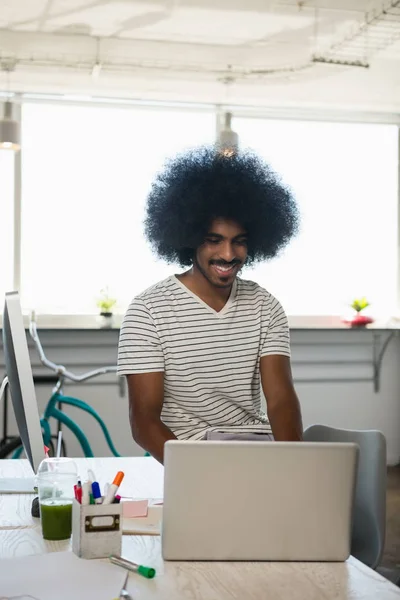 Empresário sorridente usando laptop na mesa — Fotografia de Stock