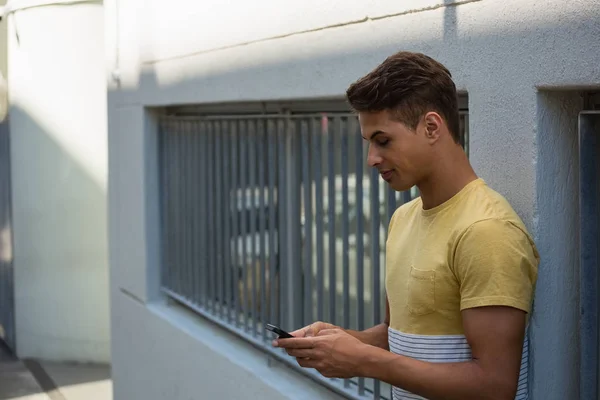 Uomo utilizzando il telefono mentre appoggiato al muro — Foto Stock