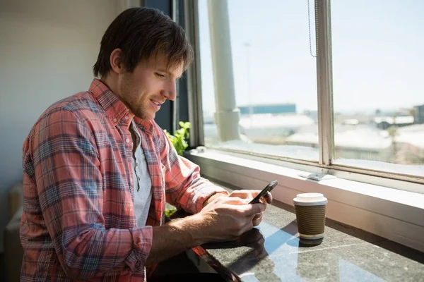 Empresario usando el teléfono mientras está sentado junto a la ventana —  Fotos de Stock