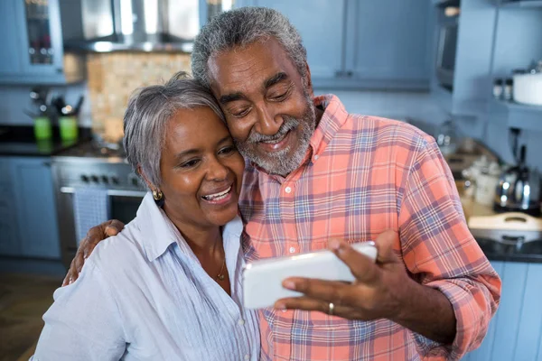 Pareja sonriente tomando selfie en casa — Foto de Stock