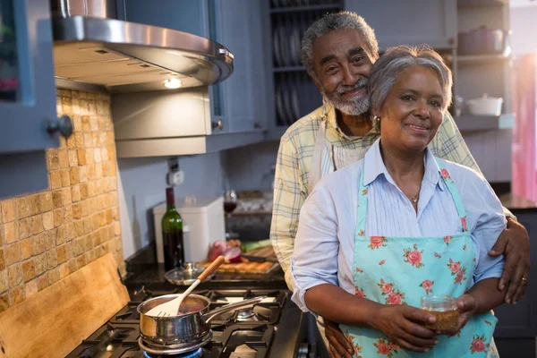 Couple standing by stove in kitchen — Stock Photo, Image